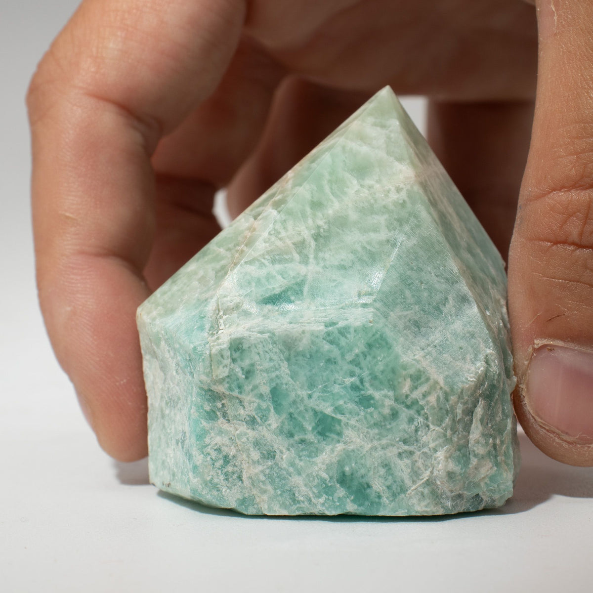 A polished green amazonite crystal point standing on cotton canvas - view 3