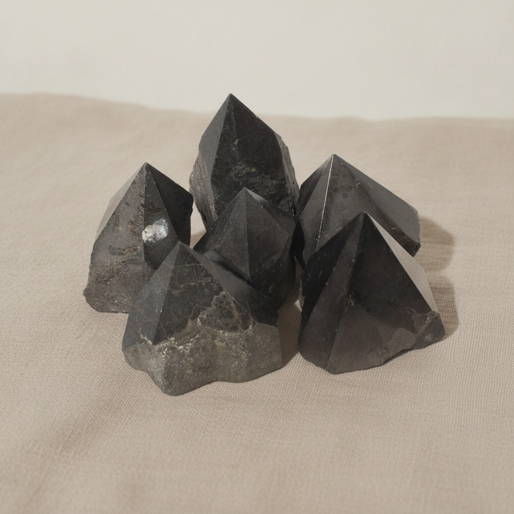 Polished black tourmaline crystal points grouped together on natural linen