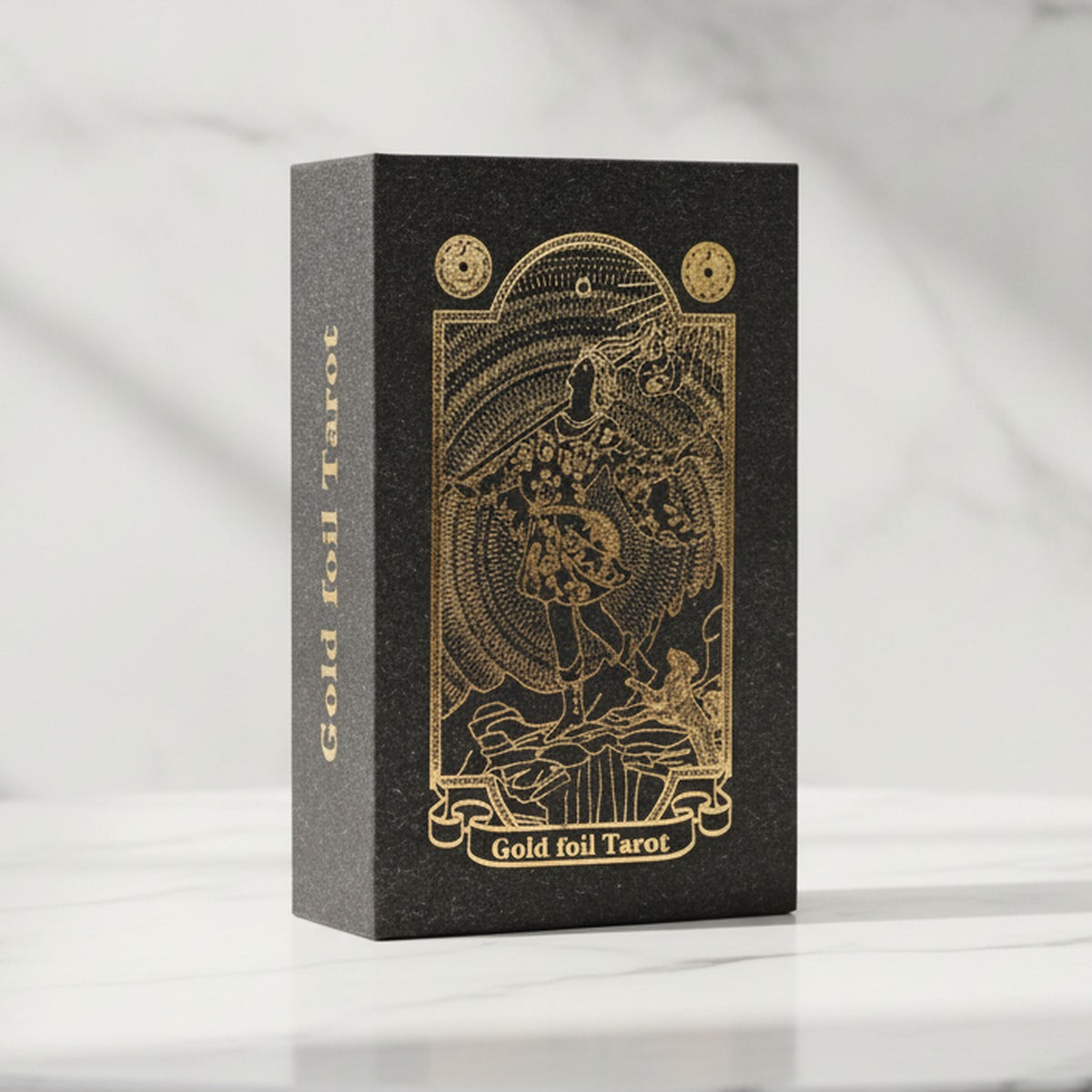 Gold foil tarot card set in its black and gold foil gift box, standing on a white marble table