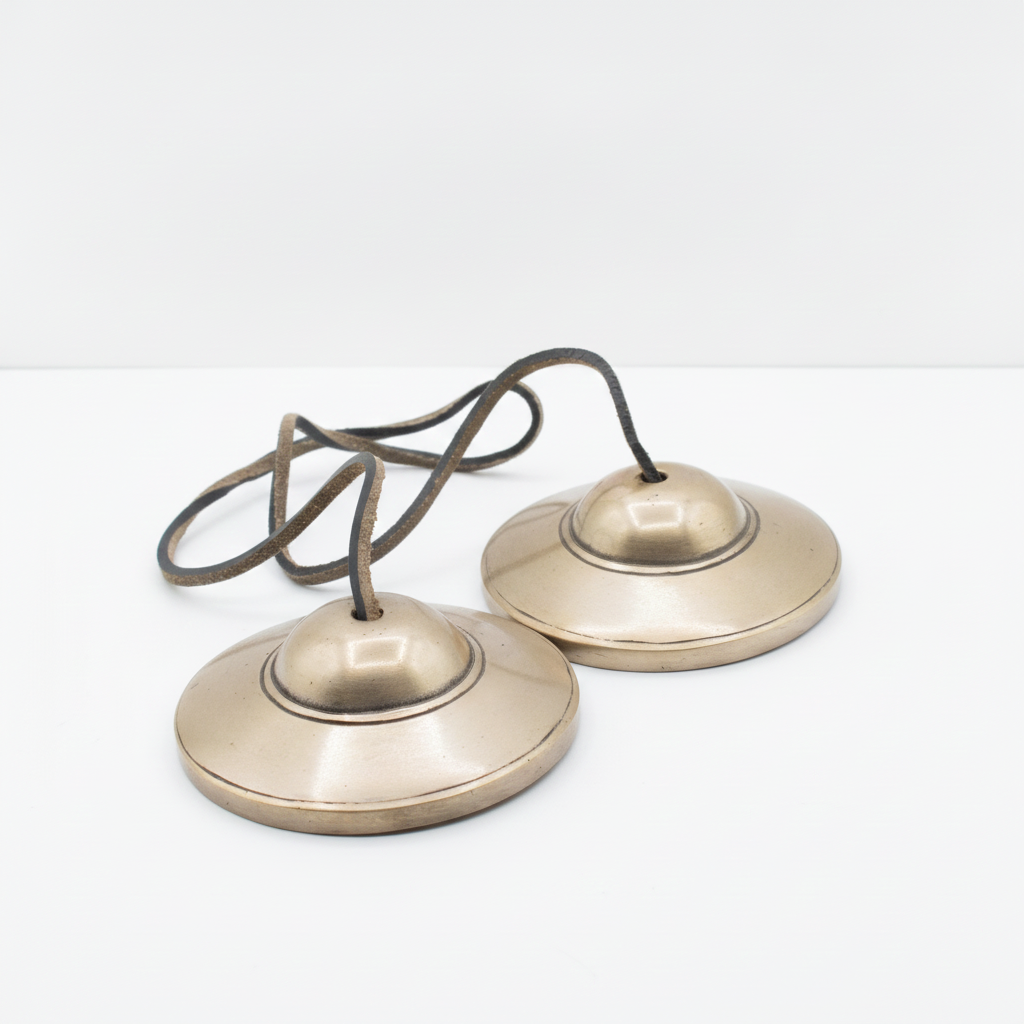 Plain brass tingsha cymbals joined by their cord