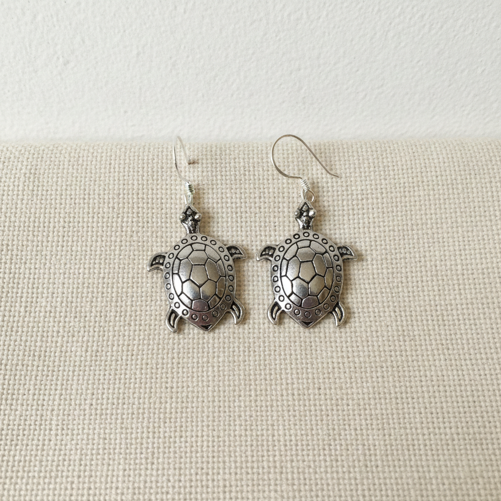 A pair of sterling silver turtle drop earrings on cotton canvas - view 3