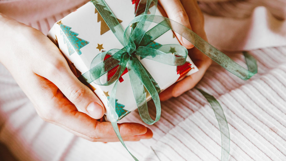 Hands holding a wrapped gift with a ribbon