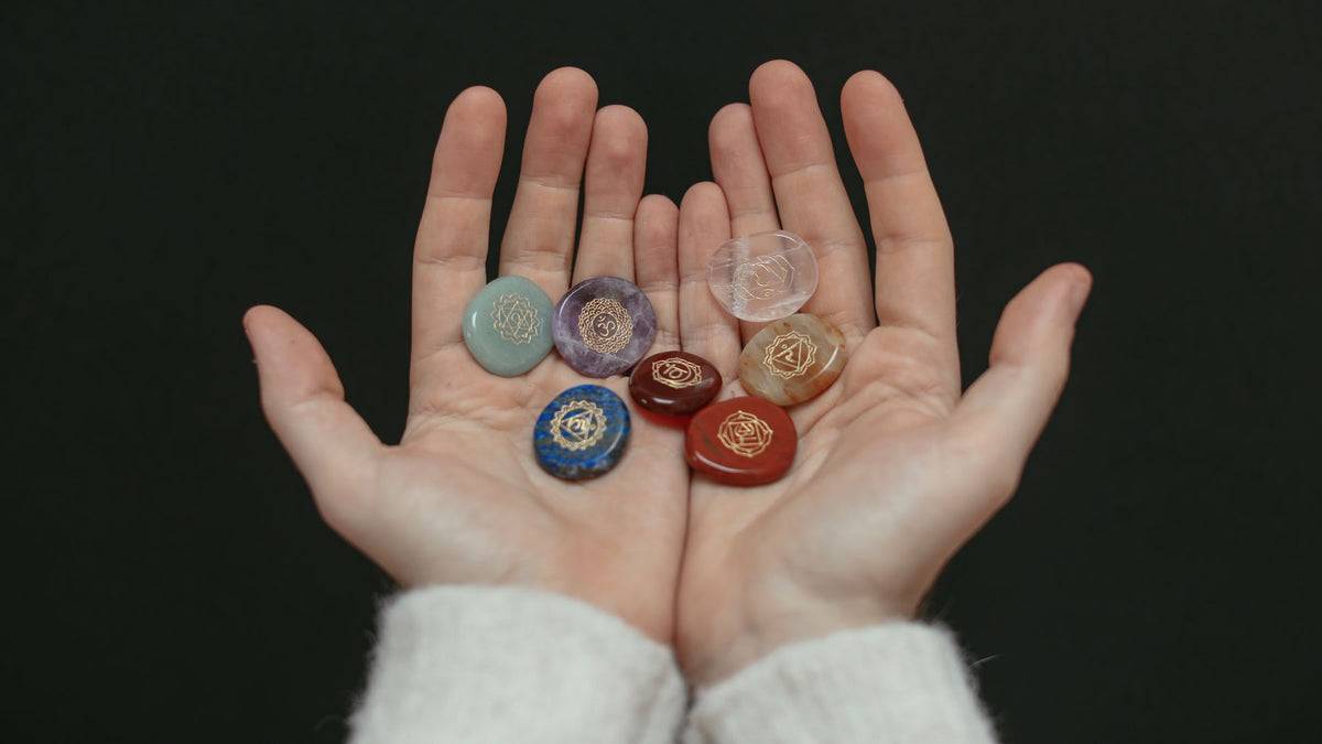 Two open hands holding a set of small polished stones