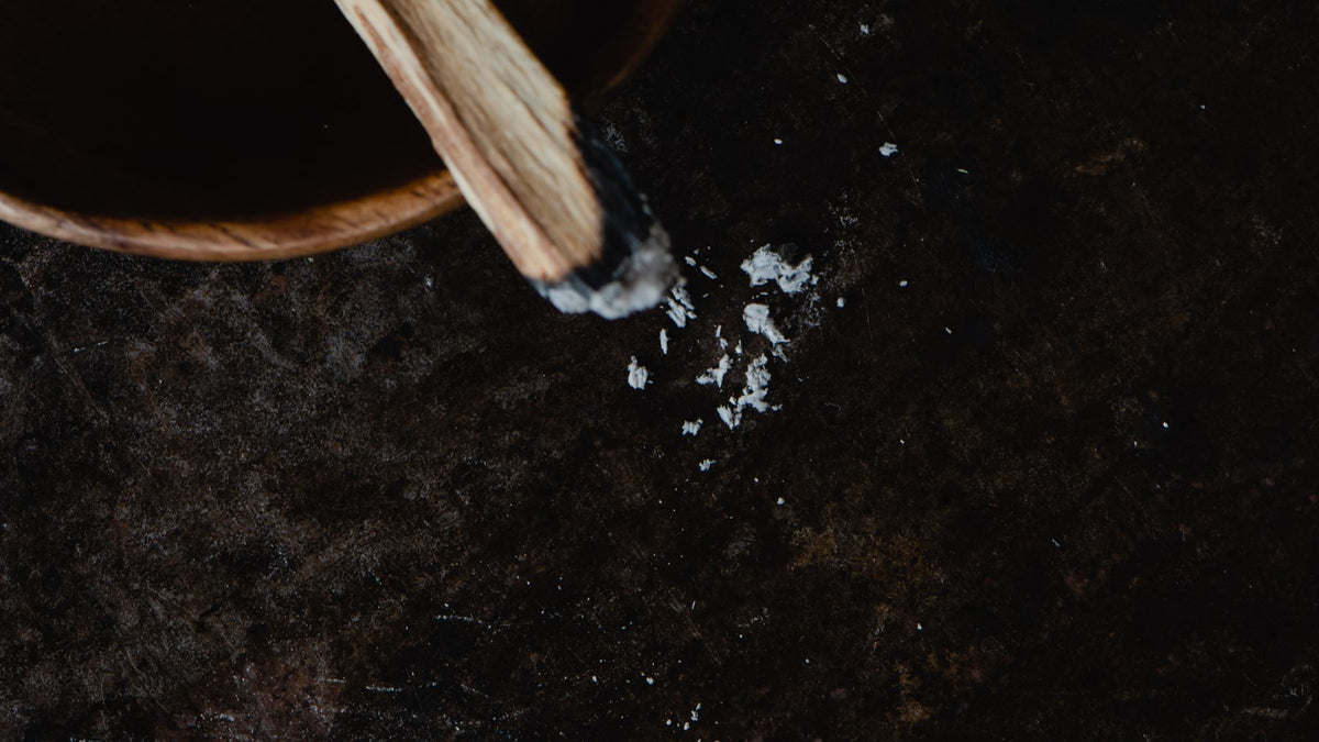 Salt being poured from a wooden bowl onto a dark surface
