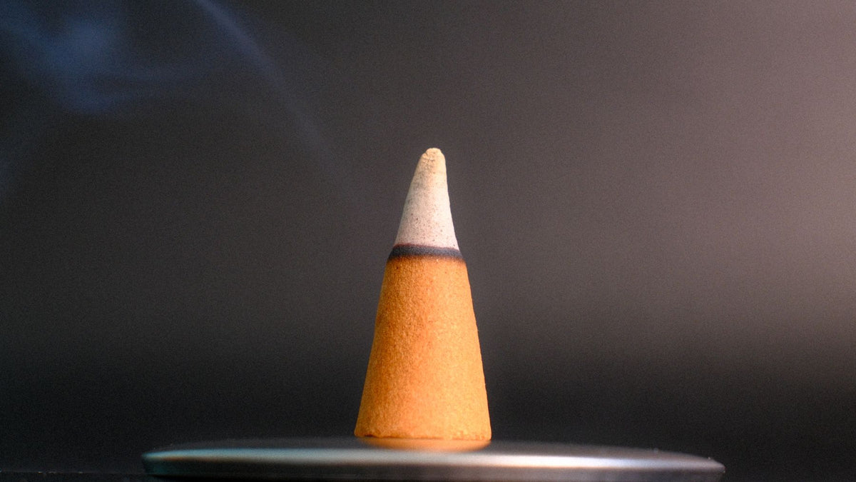An incense cone burning on a metal dish