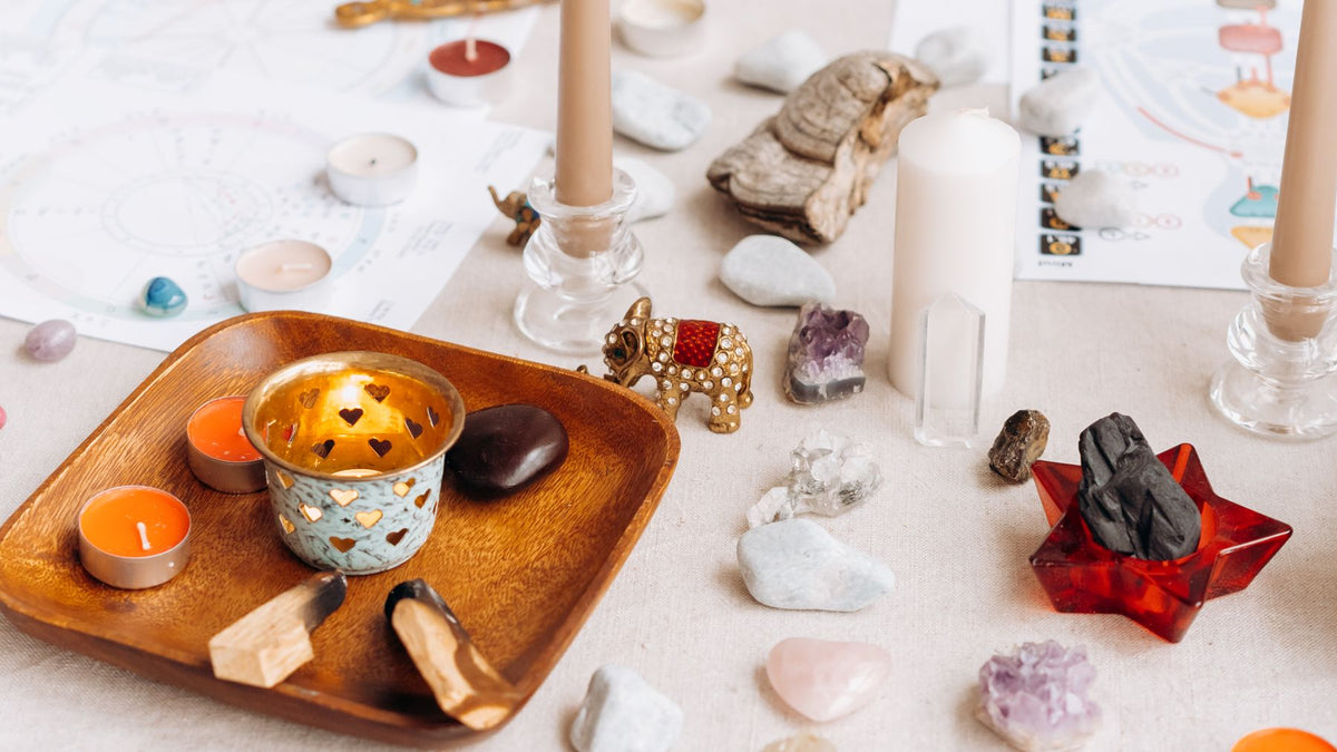 A simple home altar with candles, stones and a wooden tray
