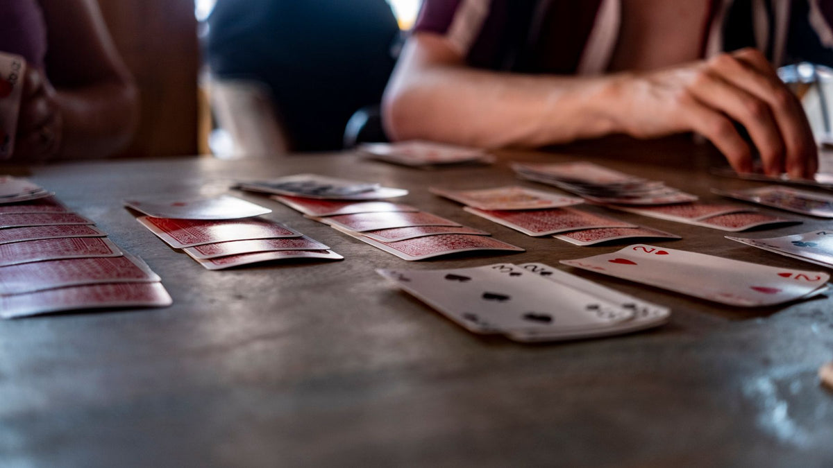 Hands playing a card game around a wooden table