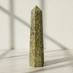 Epidote obelisk point on a marble worktop in daylight