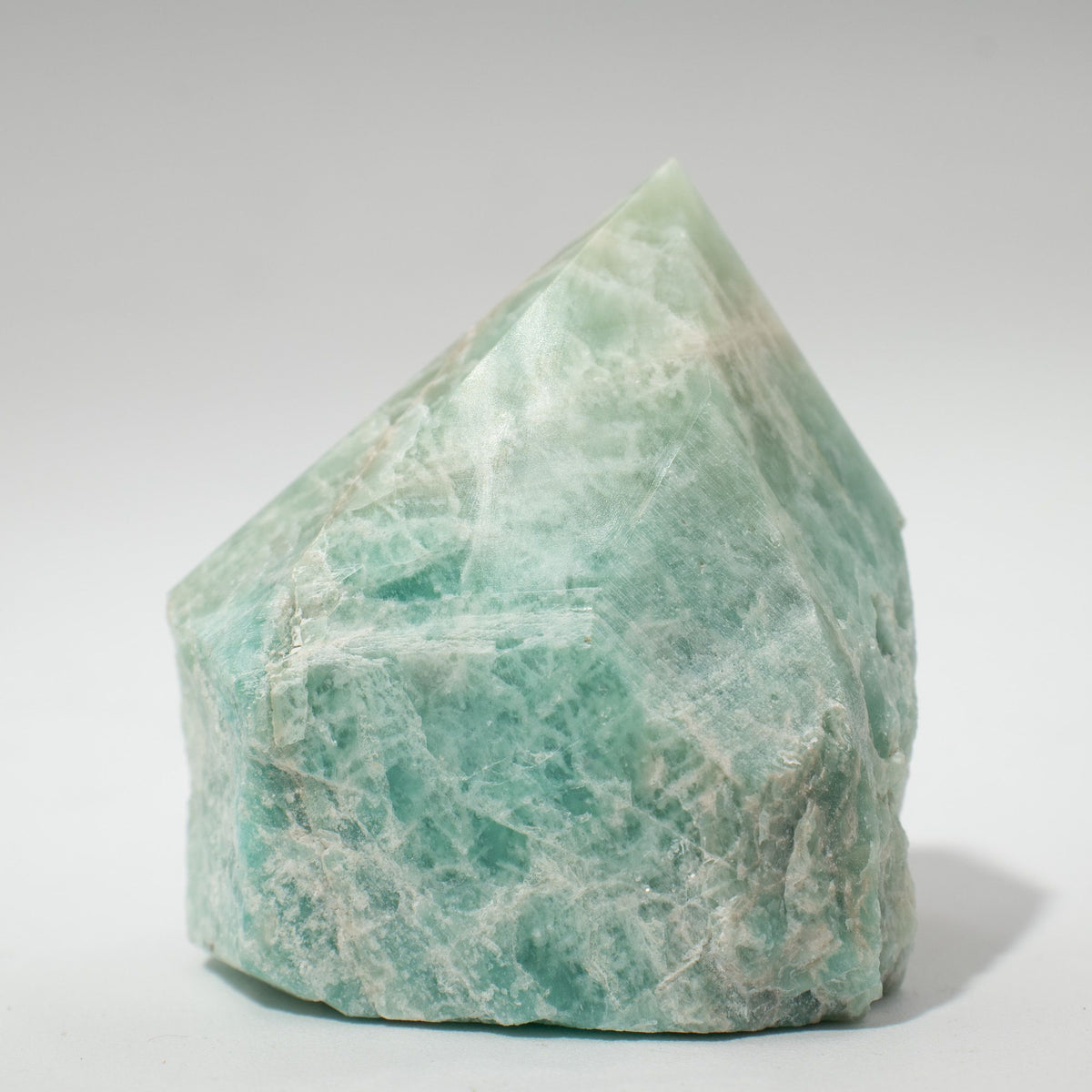 A polished green amazonite crystal point standing on cotton canvas - view 4