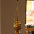 Ornate brass hanging incense burner standing on its footed base, chains beside it - view 3