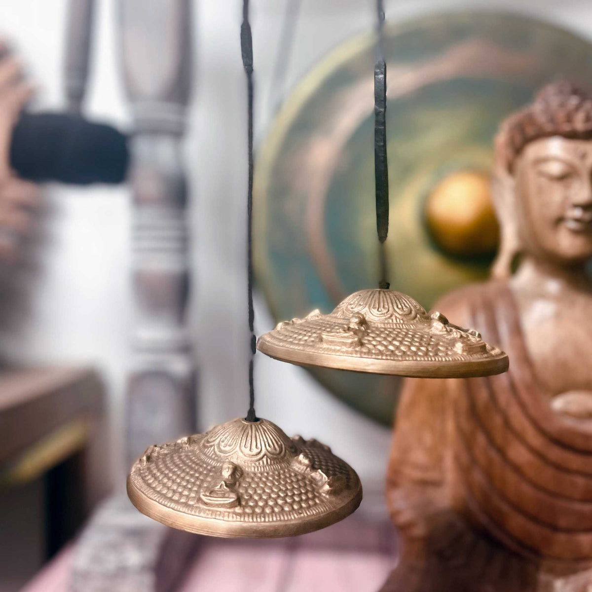 A pair of brass tingsha cymbals joined by a black cord, on cotton canvas - view 5