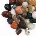 A pile of mixed tumbled gemstones in greens, reds and creams on cotton-rag paper - view 5