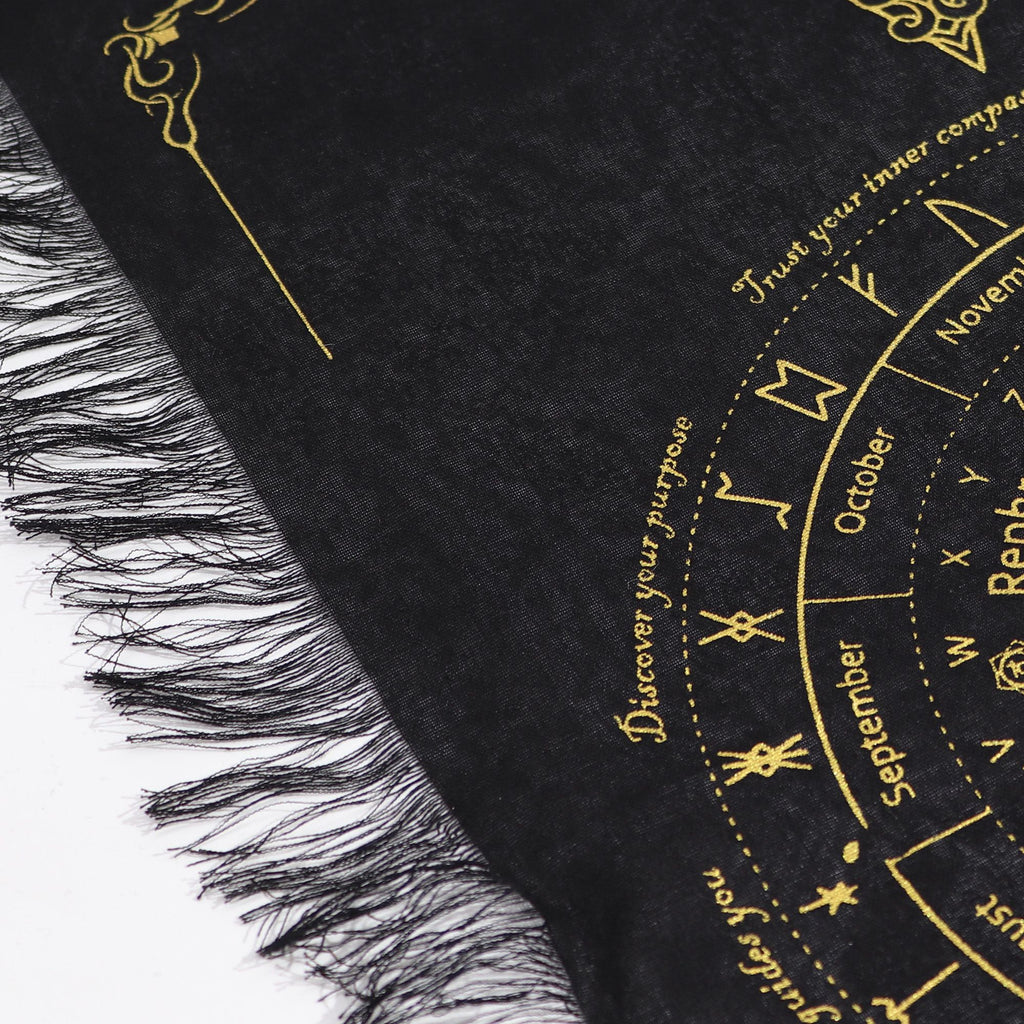 Black and gold fringed pendulum divination cloth with a sun face at the centre