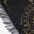 Black and gold fringed pendulum divination cloth with a sun face at the centre