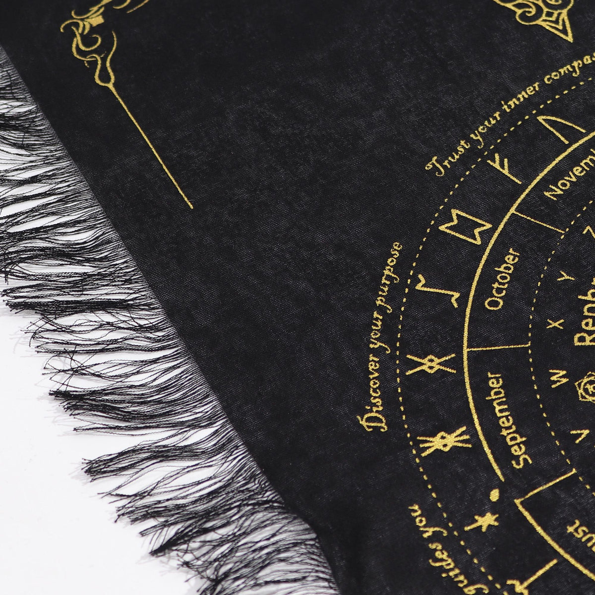 Black and gold fringed pendulum divination cloth with a sun face at the centre