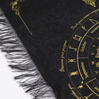Black and gold fringed pendulum divination cloth with a sun face at the centre