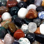 A pile of mixed tumbled gemstones in greens, reds and creams on cotton-rag paper - view 9