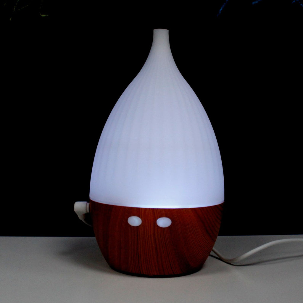 White teardrop ultrasonic aroma diffuser on a light wood base - view 3