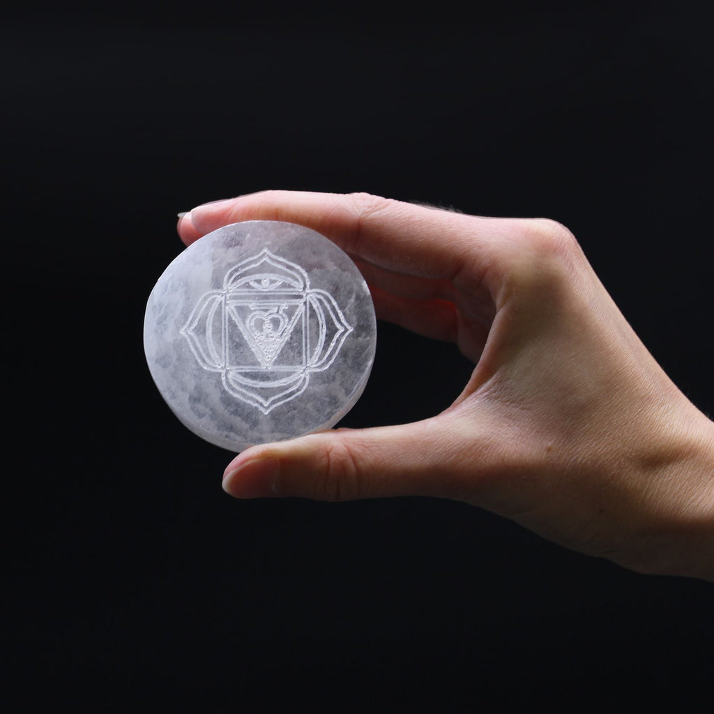 Set of seven small selenite charging plates, one engraved and coloured per chakra