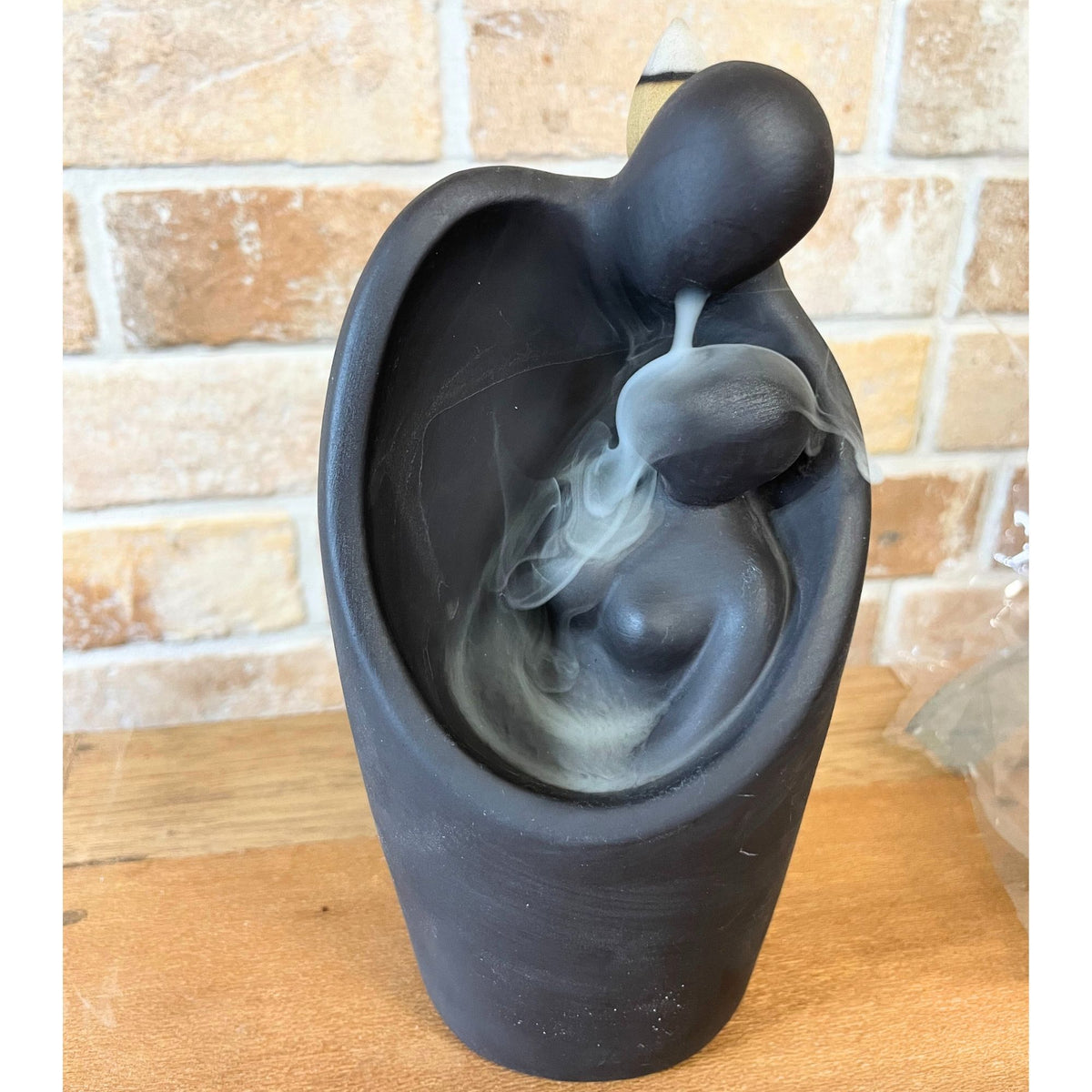 Matte black backflow burner shaped as two figures embracing, on rumpled linen - view 4