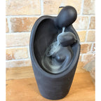 Matte black backflow burner shaped as two figures embracing, on rumpled linen - view 4