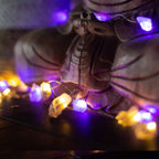 Mixed gemstone fairy lights glowing around the base of a carved wooden Buddha