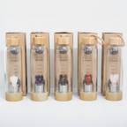Amethyst crystal glass water bottle with a carved angel inside on a clean white surface against a white wall