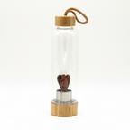 Red jasper crystal glass water bottle with a carved angel inside on a clean white surface against a white wall