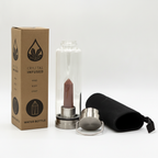 Red jasper crystal glass water bottle with an obelisk inside on a clean white surface against a white wall