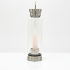 Rose quartz crystal glass water bottle with an obelisk inside on a clean white surface against a white wall