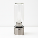 Clear quartz crystal glass water bottle on a clean white surface against a white wall