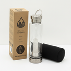 Clear quartz crystal glass water bottle on a clean white surface against a white wall