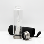 Clear quartz crystal glass water bottle on a clean white surface against a white wall