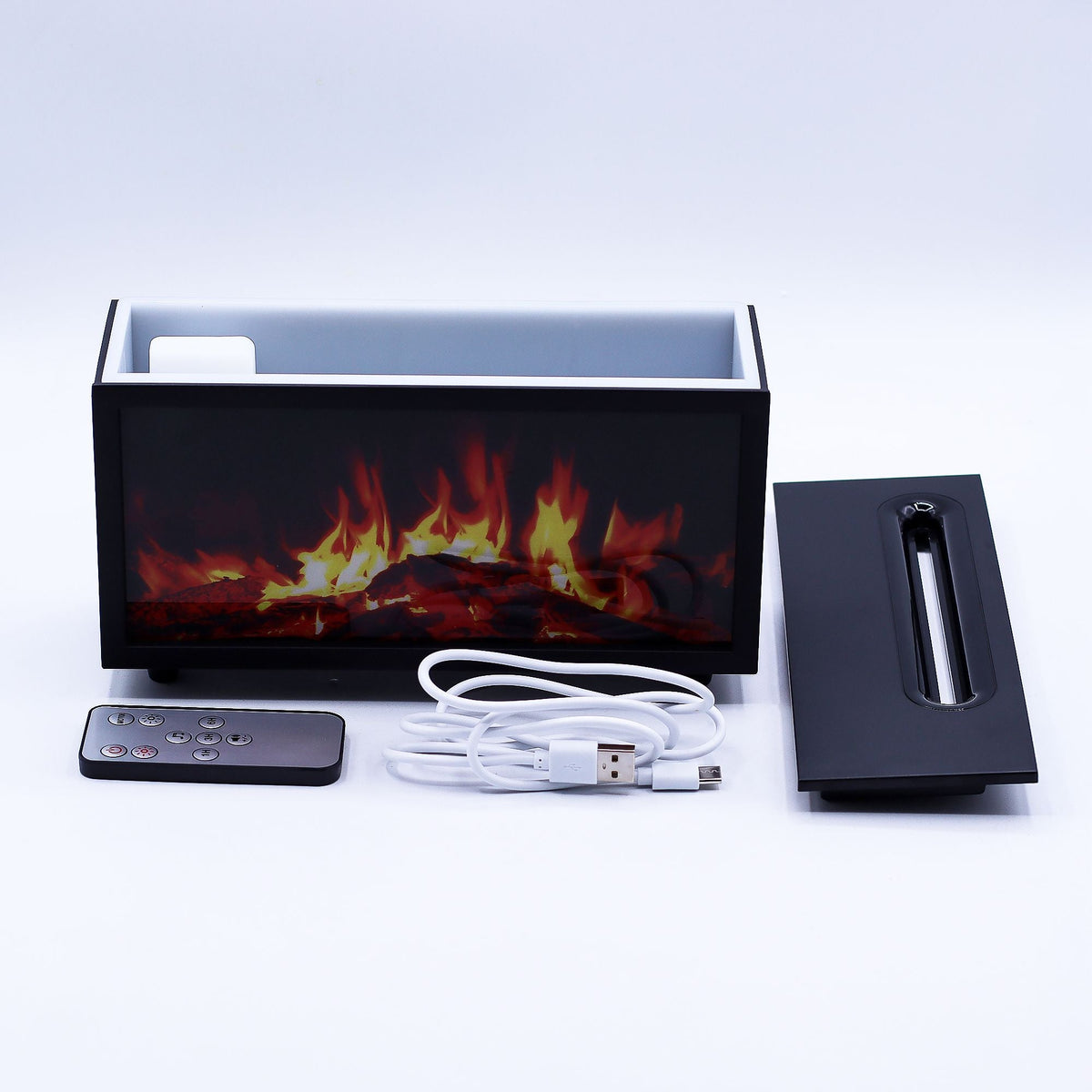 Black flame effect diffuser with its lid, remote control and USB cable laid out