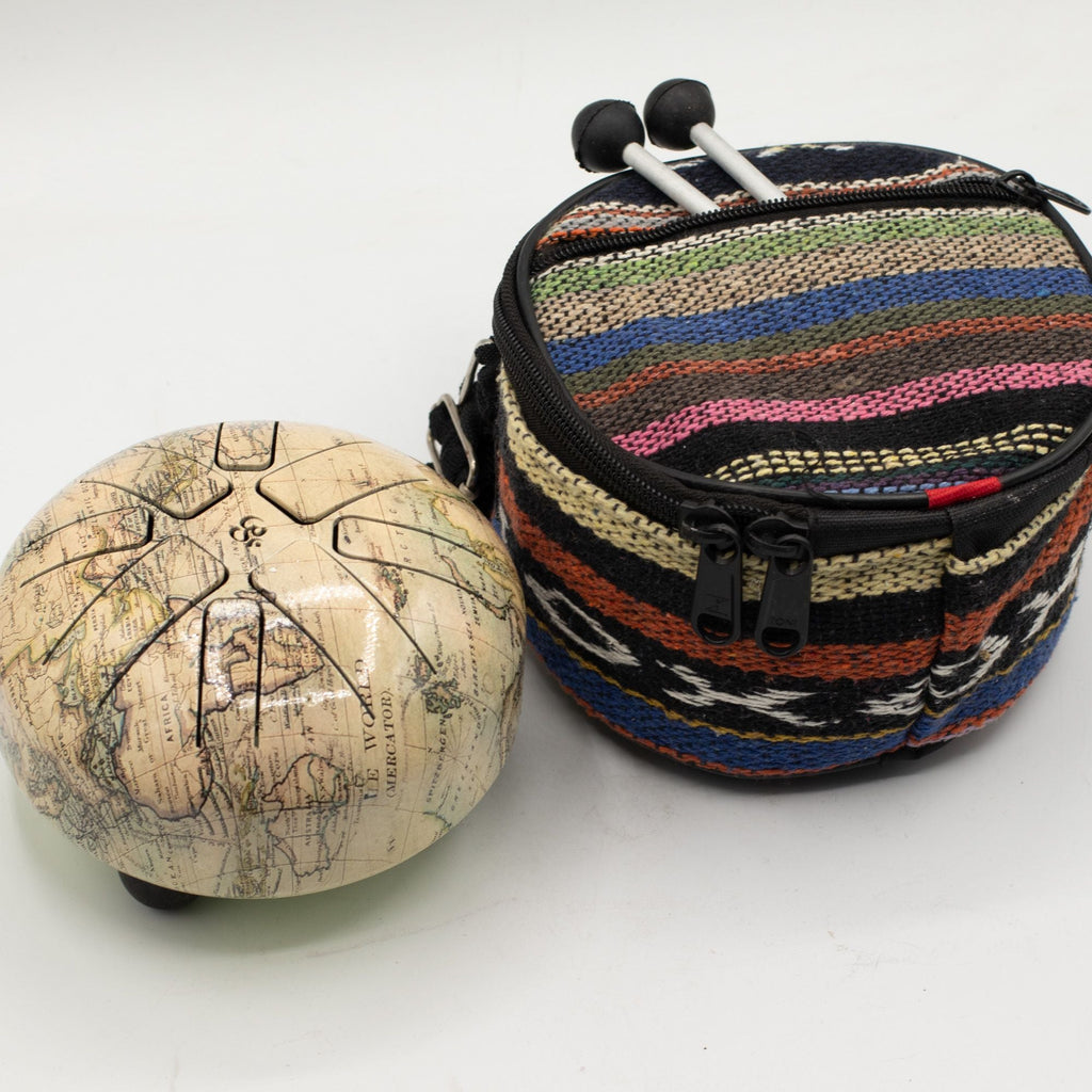 Small Atlas tongue drum beside its striped woven carry bag with the mallets