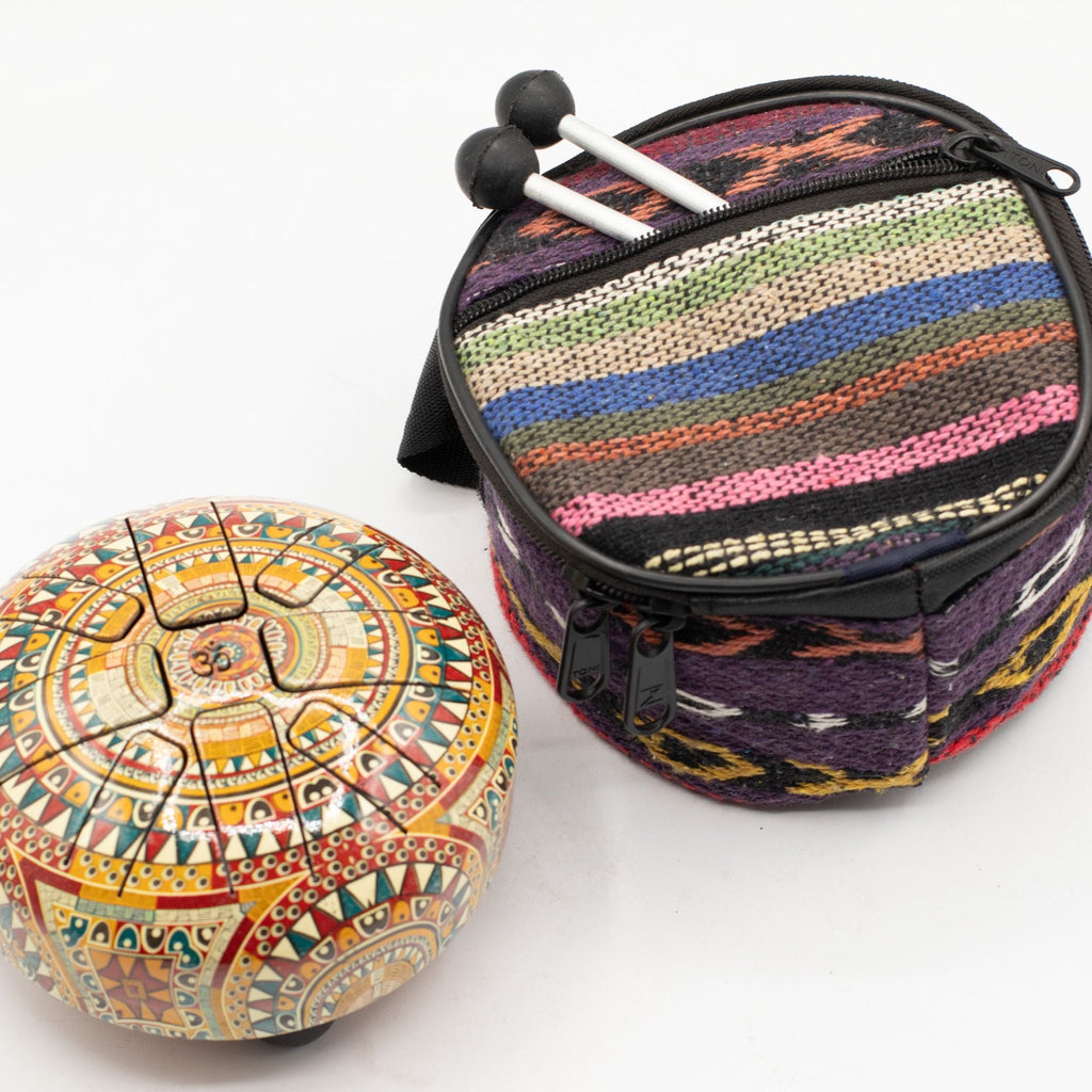 Om Mandala tongue drum beside its striped woven carry bag