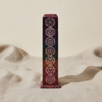 Soapstone square tower incense holder with seven chakra symbols on natural linen