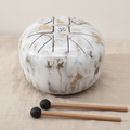 Large marble finish steel tongue drum with two mallets on natural linen