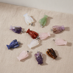 Twelve assorted gemstone mini angel pendants on natural linen