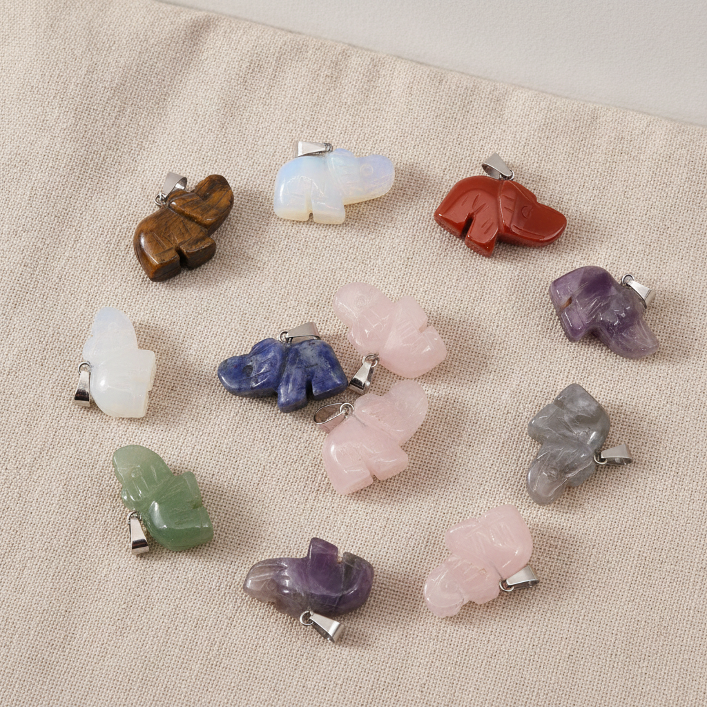 Twelve assorted gemstone lucky elephant pendants on natural linen