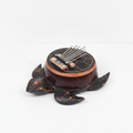 Turtle coconut shell kalimba on a clean white surface against a white wall