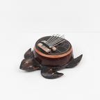 Turtle coconut shell kalimba on a clean white surface against a white wall