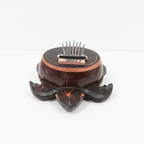 Turtle coconut shell kalimba on a clean white surface against a white wall