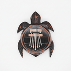 Turtle coconut shell kalimba on a clean white surface against a white wall