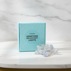 Celestite crystal fairy lights on a marble table with a marble wall behind