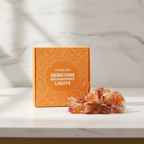 Orange jade crystal fairy lights on a marble table with a marble wall behind