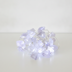 Clear quartz crystal fairy lights on a clean white surface against a white wall