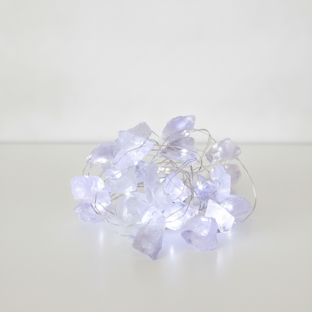 Clear quartz crystal fairy lights on a clean white surface against a white wall