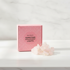 Rose quartz crystal fairy lights on a marble table with a marble wall behind