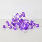 Amethyst crystal fairy lights on a clean white surface against a white wall